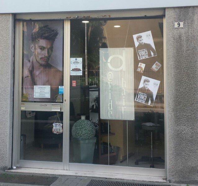 La vetrina del salone d@vide h@ir con l'insegna e i poster American Crew